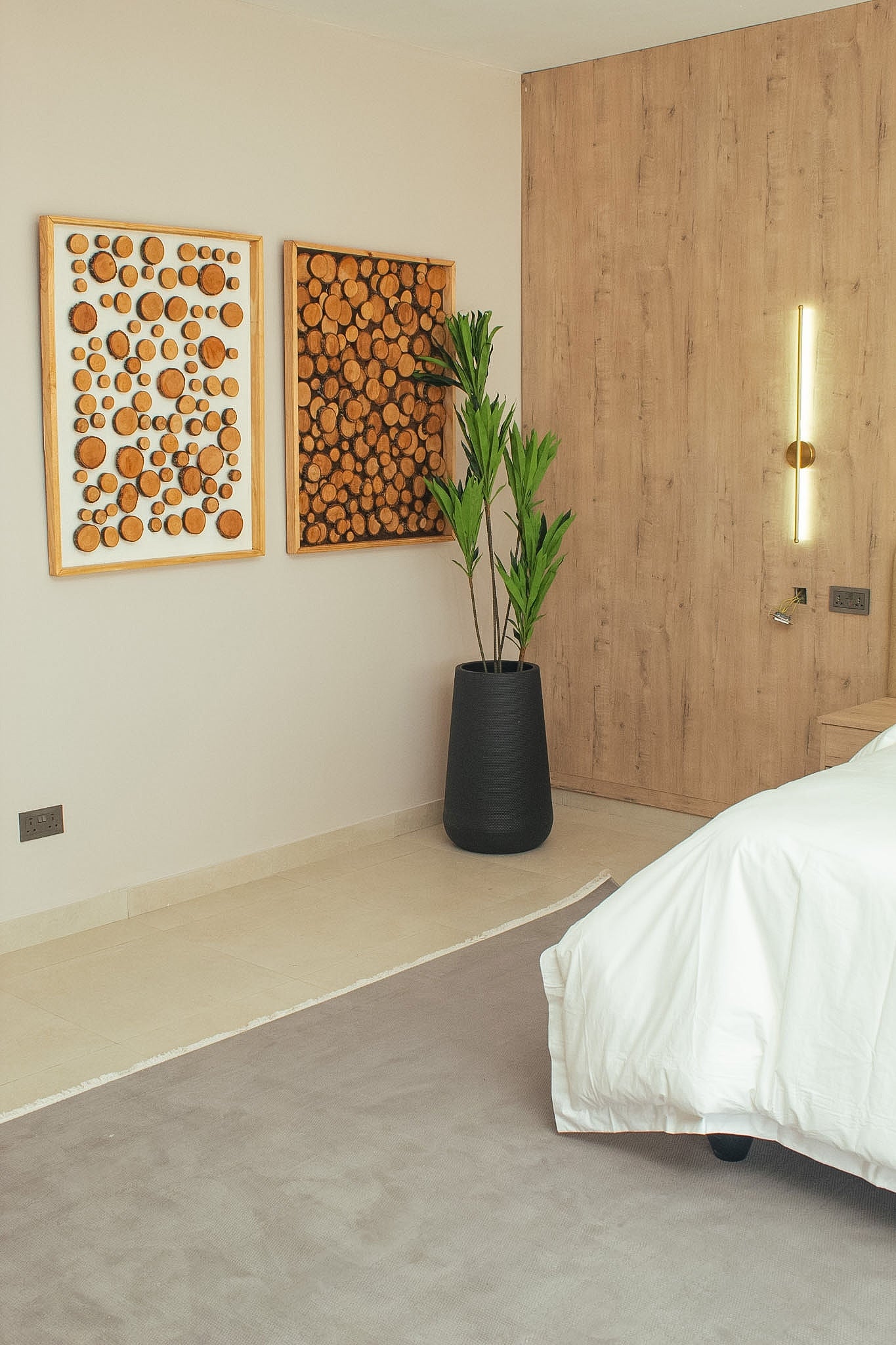 Modern bedroom with wooden wall art, plant, and wardrobe.